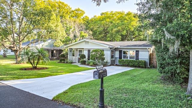 A single-story house with a gray and white exterior sits behind a grassy front lawn — 5725 14TH STREET, ZEPHYRHILLS, FL