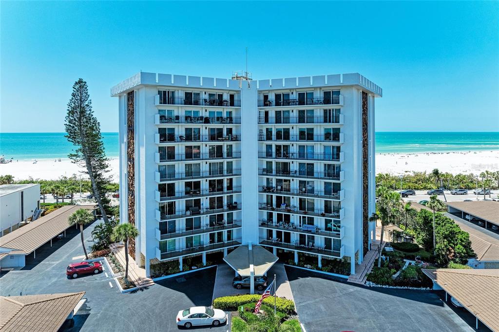 An aerial view of a multi-story white condominium building located directly on a sandy beach — 101 BENJAMIN FRANKLIN DRIVE UNIT 46, SARASOTA, FL