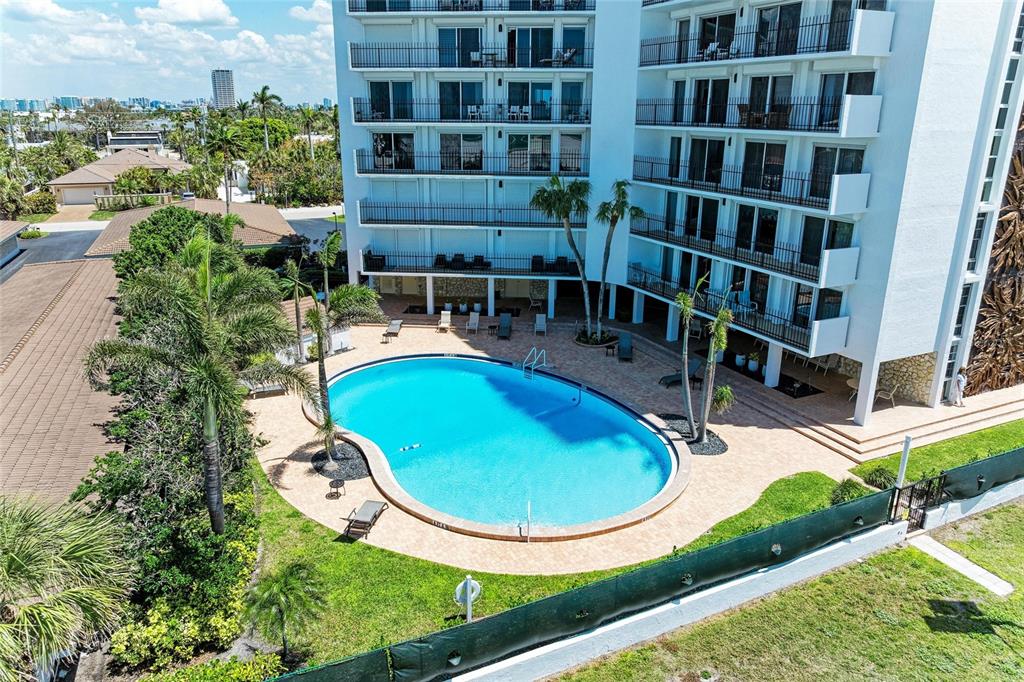 An aerial view shows a swimming pool surrounded by a patio and a multi-story building — 101 BENJAMIN FRANKLIN DRIVE UNIT 46, SARASOTA, FL