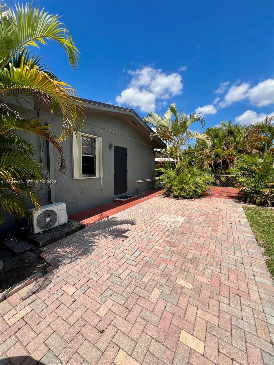 A gray house exterior features a brick-paved patio, a window, and an outdoor AC unit — 5410 W 7th Ave # 1, Hialeah FL 33012, HIALEAH, FL