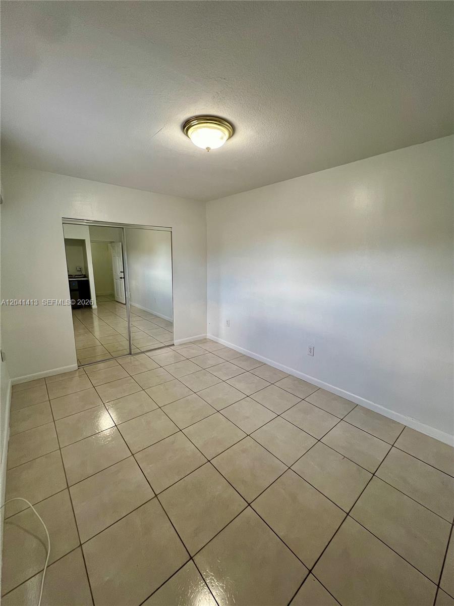A room with light-colored floor tiles, white walls, and mirrored sliding closet doors — 5410 W 7th Ave # 1, Hialeah FL 33012, HIALEAH, FL