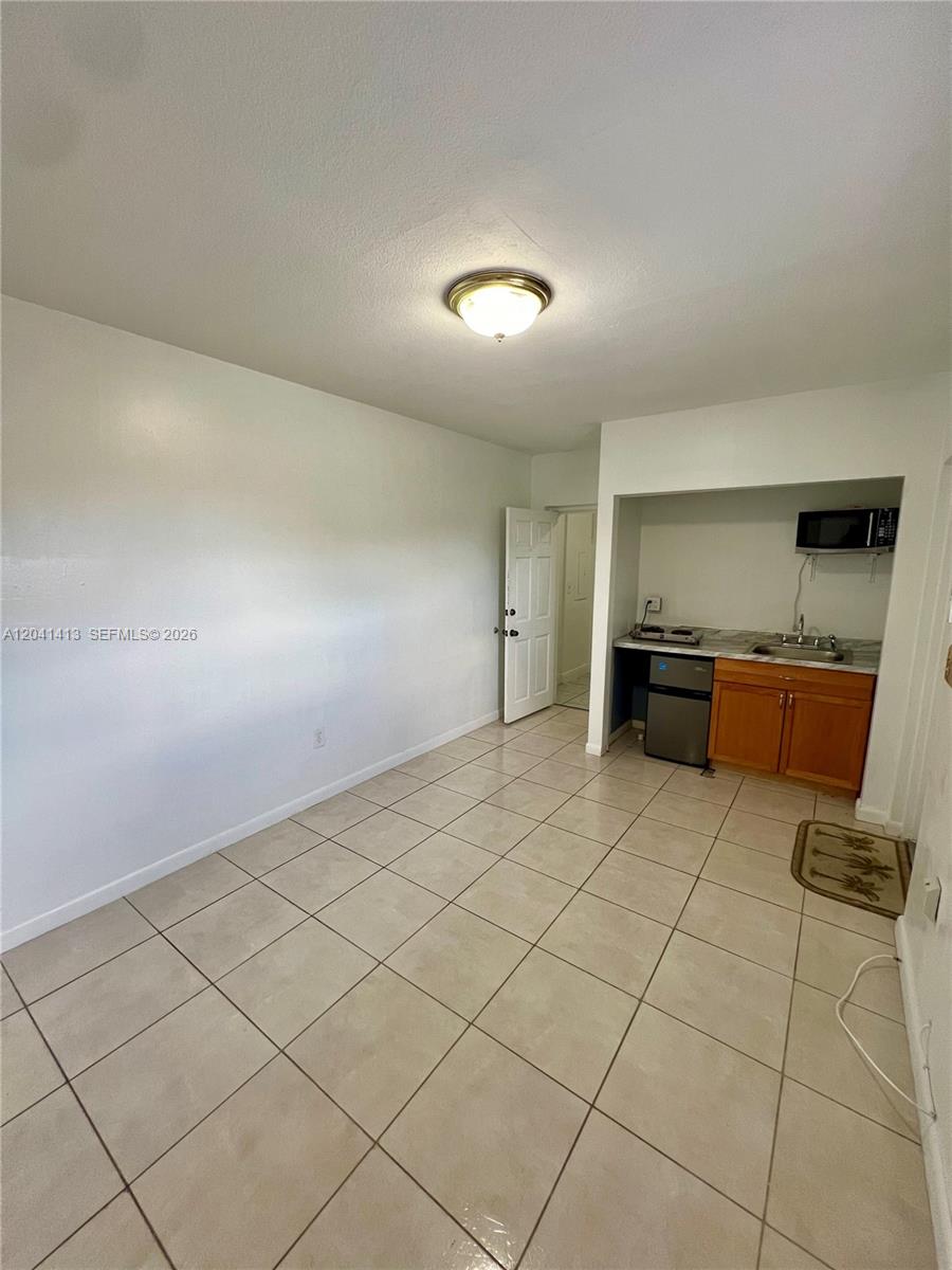 This room features light-colored tile flooring, white walls, and a small kitchenette area — 5410 W 7th Ave # 1, Hialeah FL 33012, HIALEAH, FL