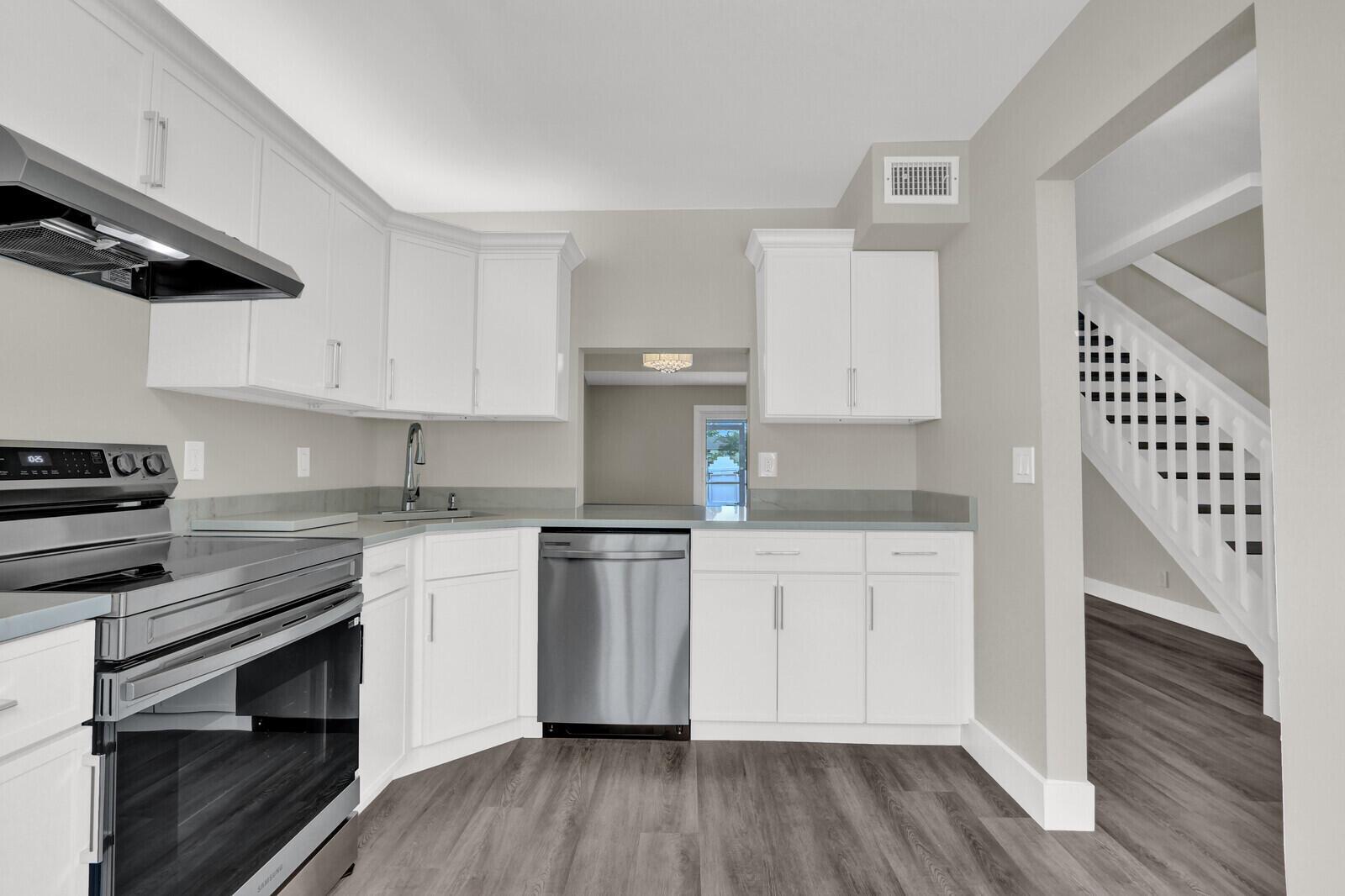 A kitchen with white cabinets, stainless steel appliances, gray countertops, and wood-look flooring — 234 Foxtail Drive, FL 33415, FL