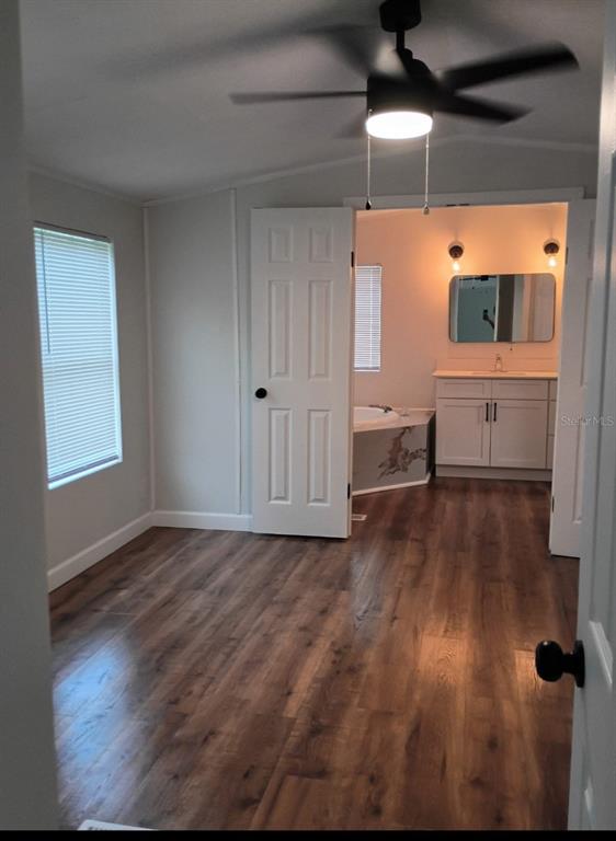 A bedroom with wood-look flooring leads through double doors into a bathroom with a vanity — 105 CANARY LANE, SATSUMA, FL