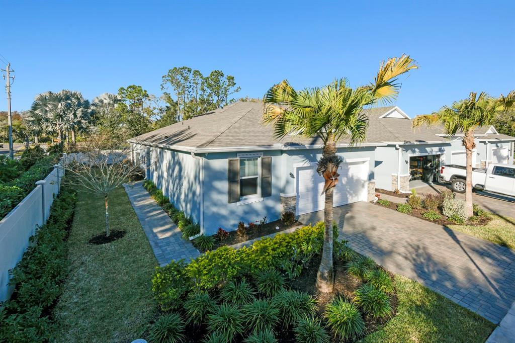 The exterior of a light blue house features a paved driveway, palm trees, and landscaping — 810 RUDDY QUAIL PLACE, SUN CITY CENTER, FL