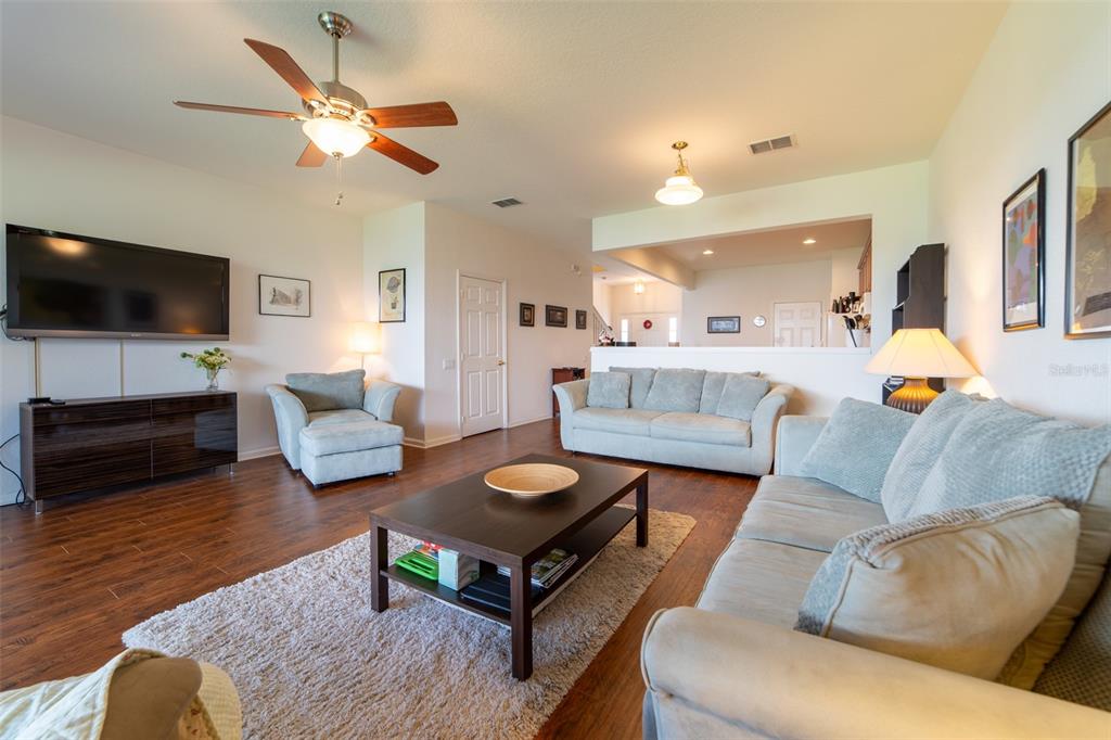 A living room features wood-look flooring, a ceiling fan, a television, and light-colored furniture — 974 ENCLAIR STREET, ORLANDO, FL