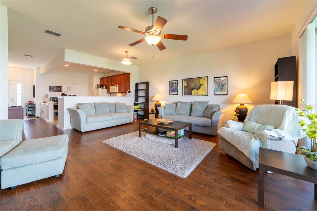 A living room with wood-look tile floors, two sofas, an armchair, and an open kitchen — 974 ENCLAIR STREET, ORLANDO, FL