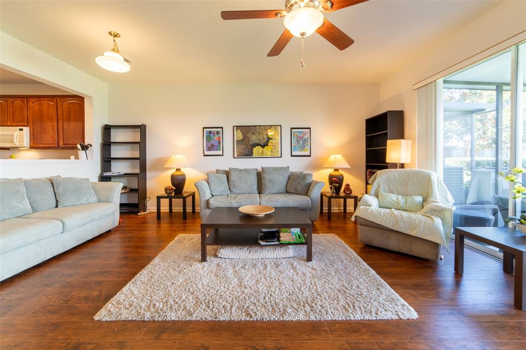A living room features wood-look flooring, a beige area rug, and a ceiling fan — 974 ENCLAIR STREET, ORLANDO, FL