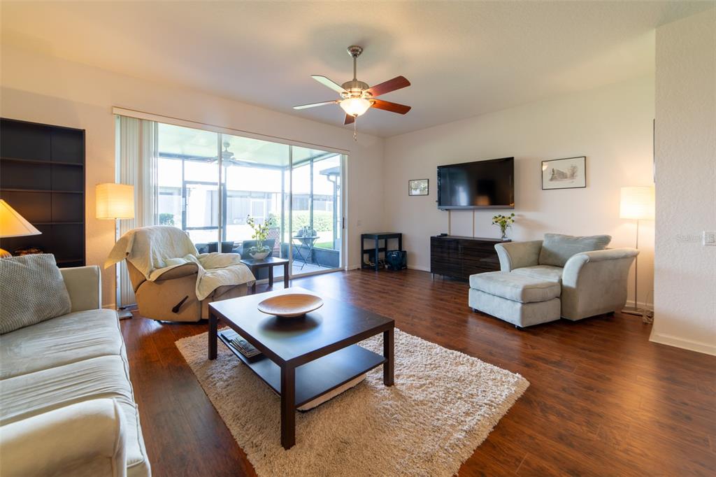 A living room with wood flooring, a ceiling fan, a television, and a sliding glass door — 974 ENCLAIR STREET, ORLANDO, FL