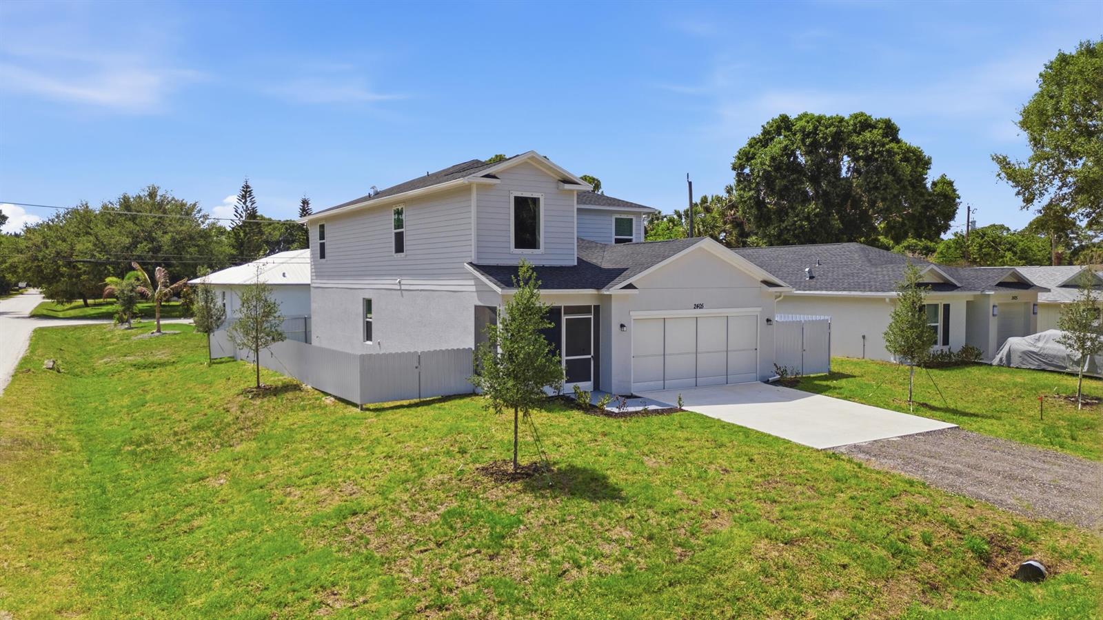 A two-story house with light gray siding and a white garage sits on a lawn — 2405 88th Avenue, Vero Beach FL 32966, VERO BEACH, FL
