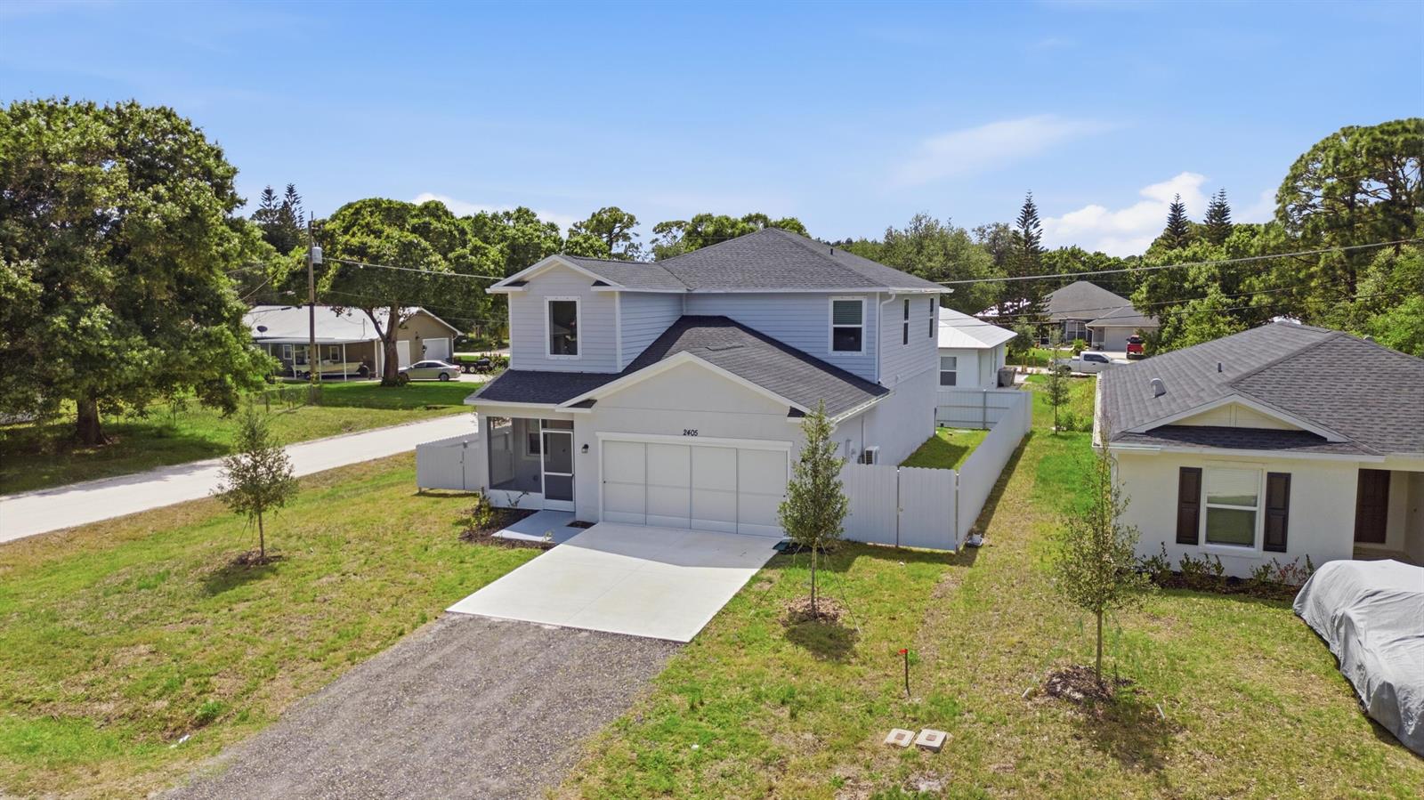 An aerial view shows a two-story light blue house with a white garage and driveway — 2405 88th Avenue, Vero Beach FL 32966, VERO BEACH, FL