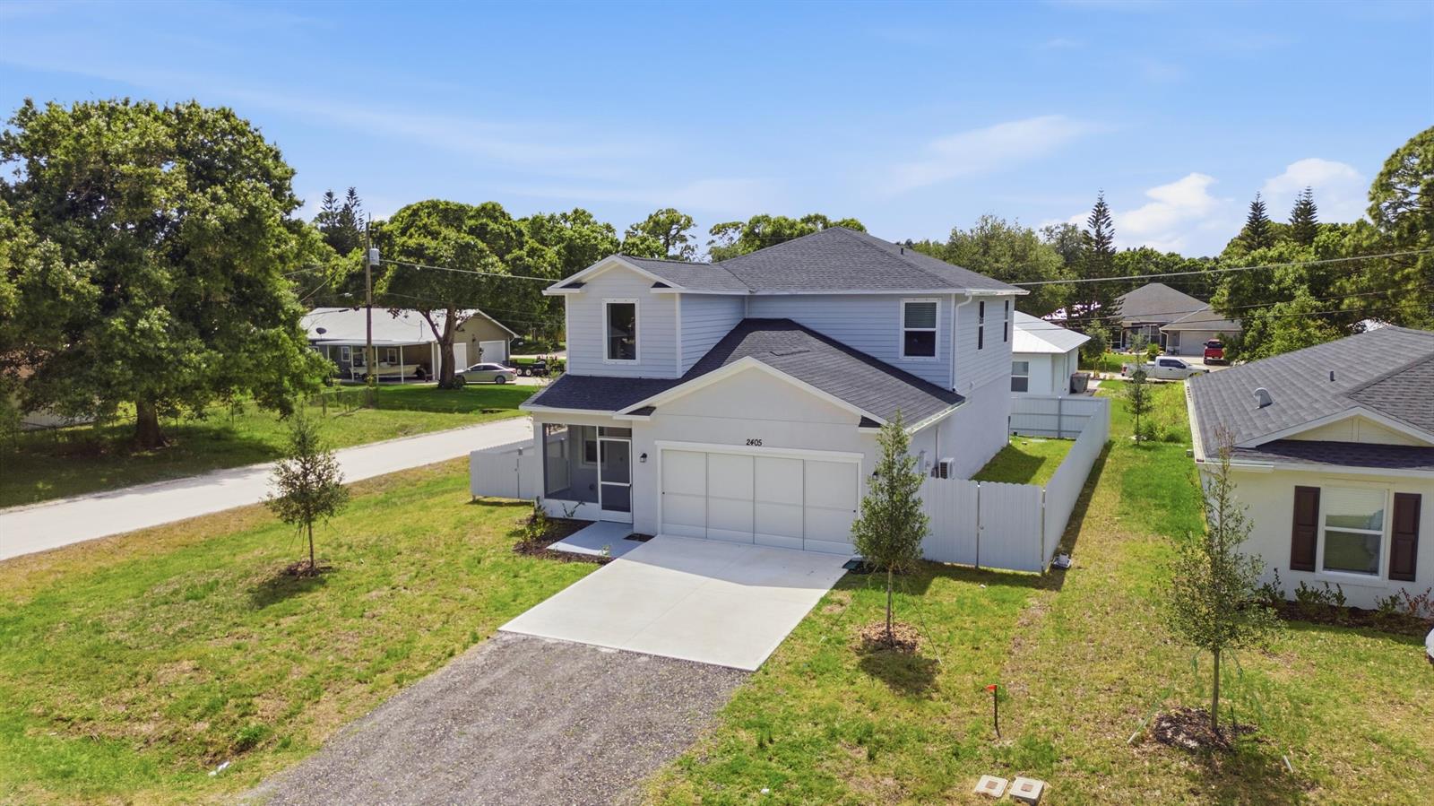 An aerial view of a two-story light blue house with a white garage and driveway — 2405 88th Avenue, Vero Beach FL 32966, VERO BEACH, FL