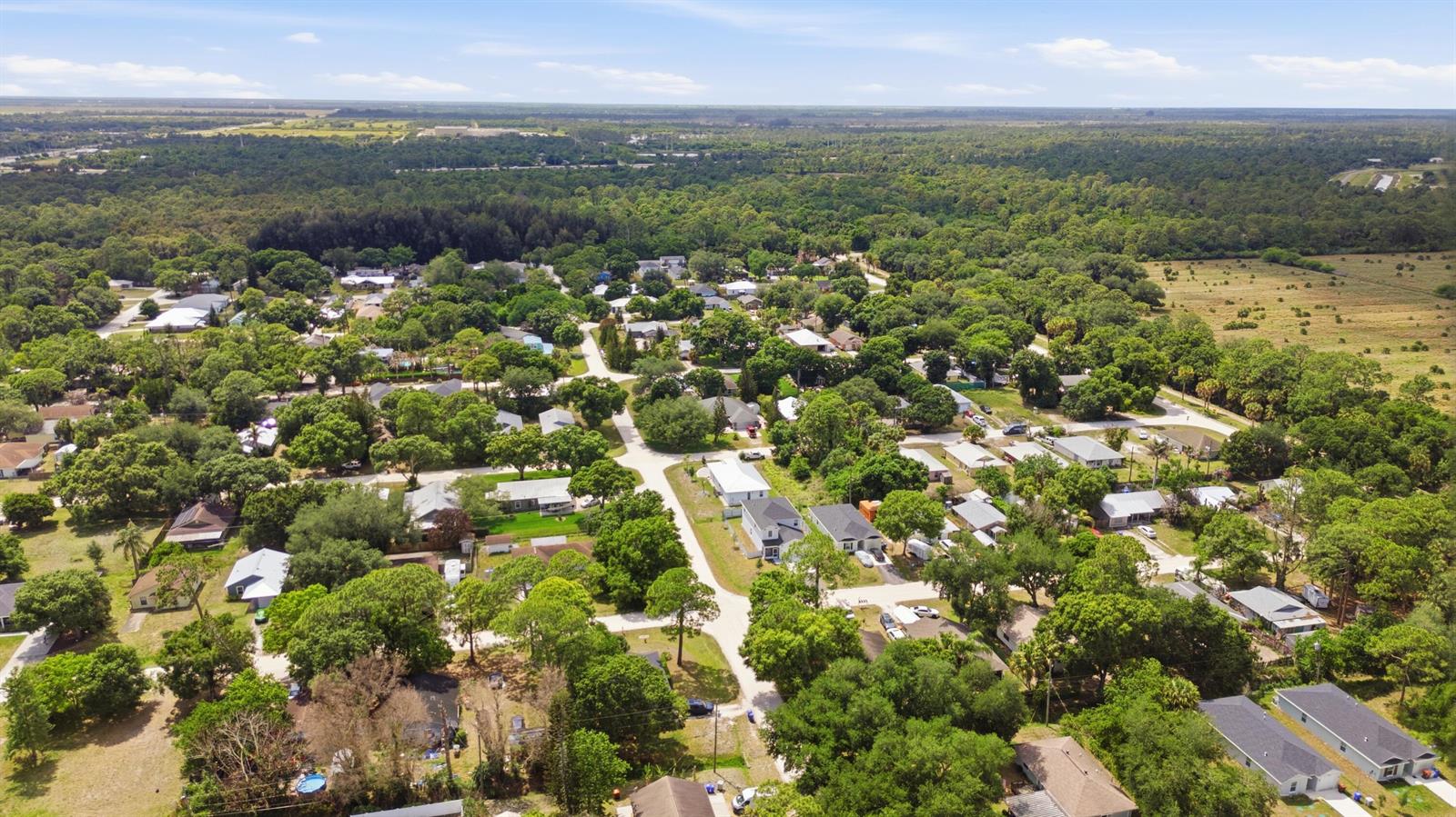 An aerial view shows a residential neighborhood surrounded by dense trees and open fields — 2405 88th Avenue, Vero Beach FL 32966, VERO BEACH, FL