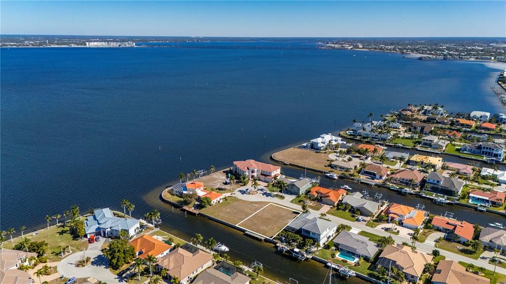 An aerial view shows a vacant waterfront lot situated between residential homes along a canal — 7 TROPICANA DRIVE, PUNTA GORDA, FL