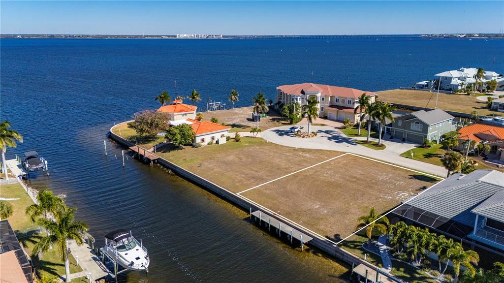 An aerial view shows a vacant waterfront lot with a white outline near houses — 7 TROPICANA DRIVE, PUNTA GORDA, FL