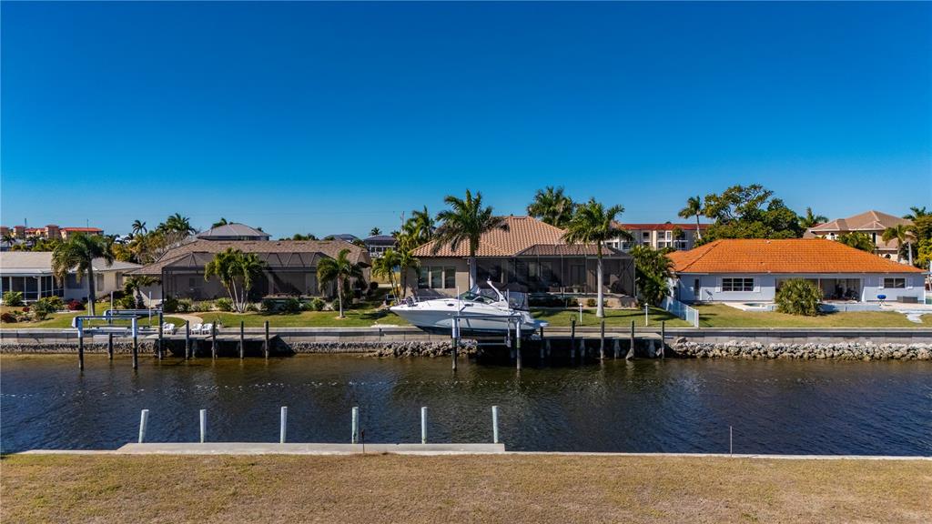 An aerial view shows waterfront houses with boat docks and a boat on a lift — 7 TROPICANA DRIVE, PUNTA GORDA, FL
