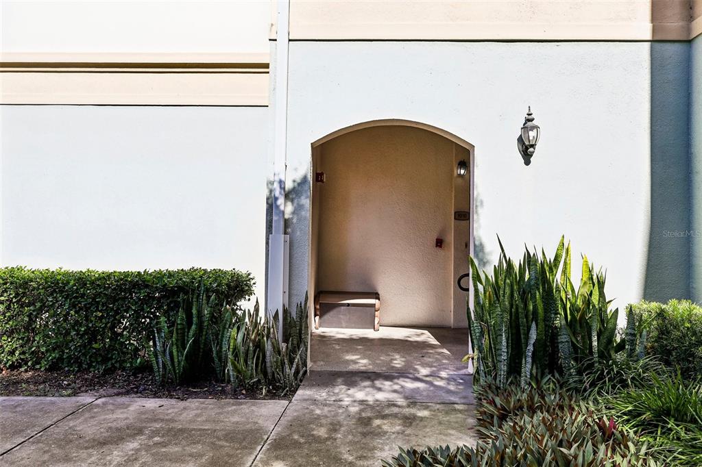 An arched entryway leads to a recessed front door with a small bench outside — 11446 JASPER KAY TERRACE UNIT 103, WINDERMERE, FL