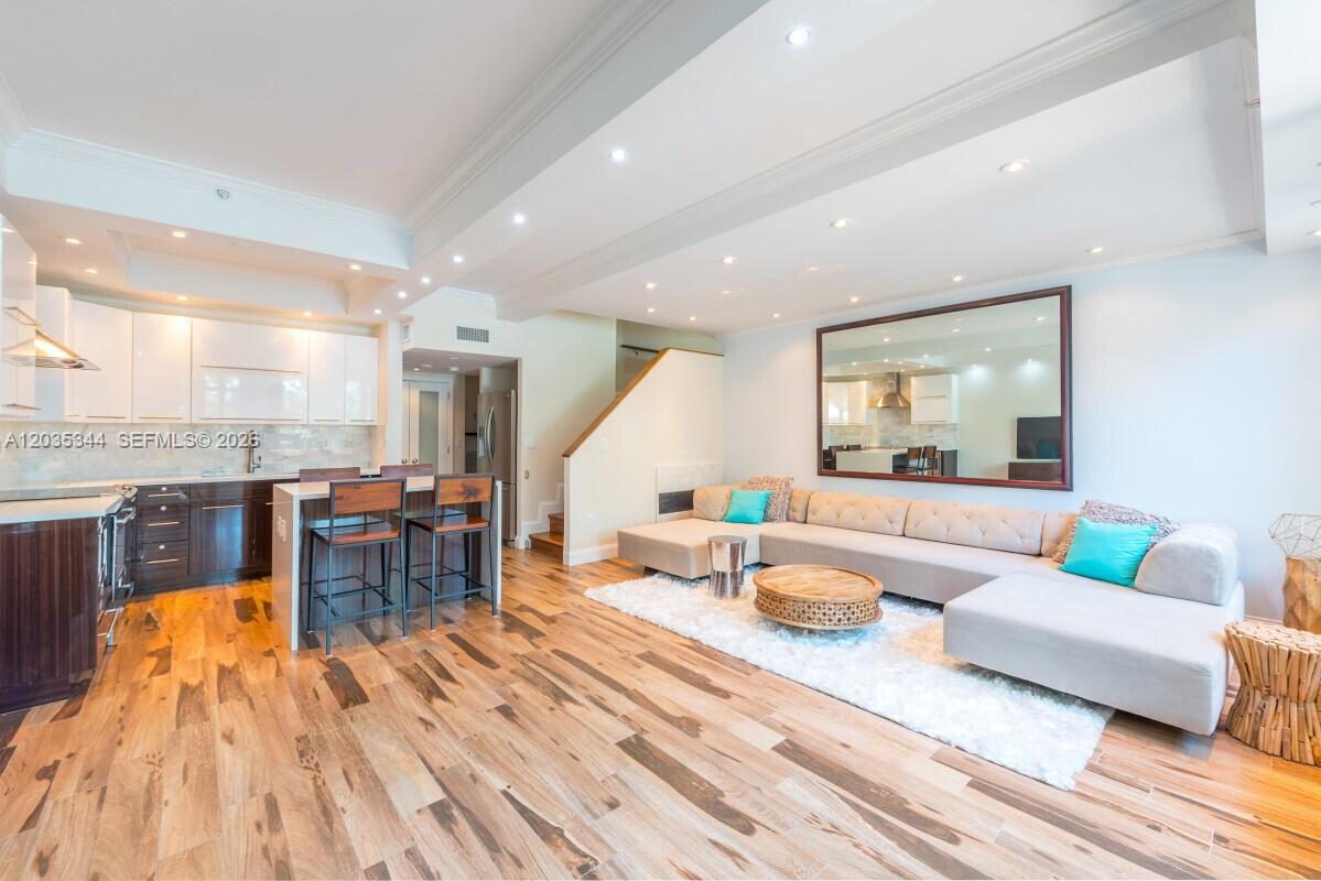 A modern open-concept living room and kitchen feature hardwood floors and a large sectional sofa — 400 S Pointe Dr # 307, Miami Beach FL 33139, MIAMI BEACH, FL
