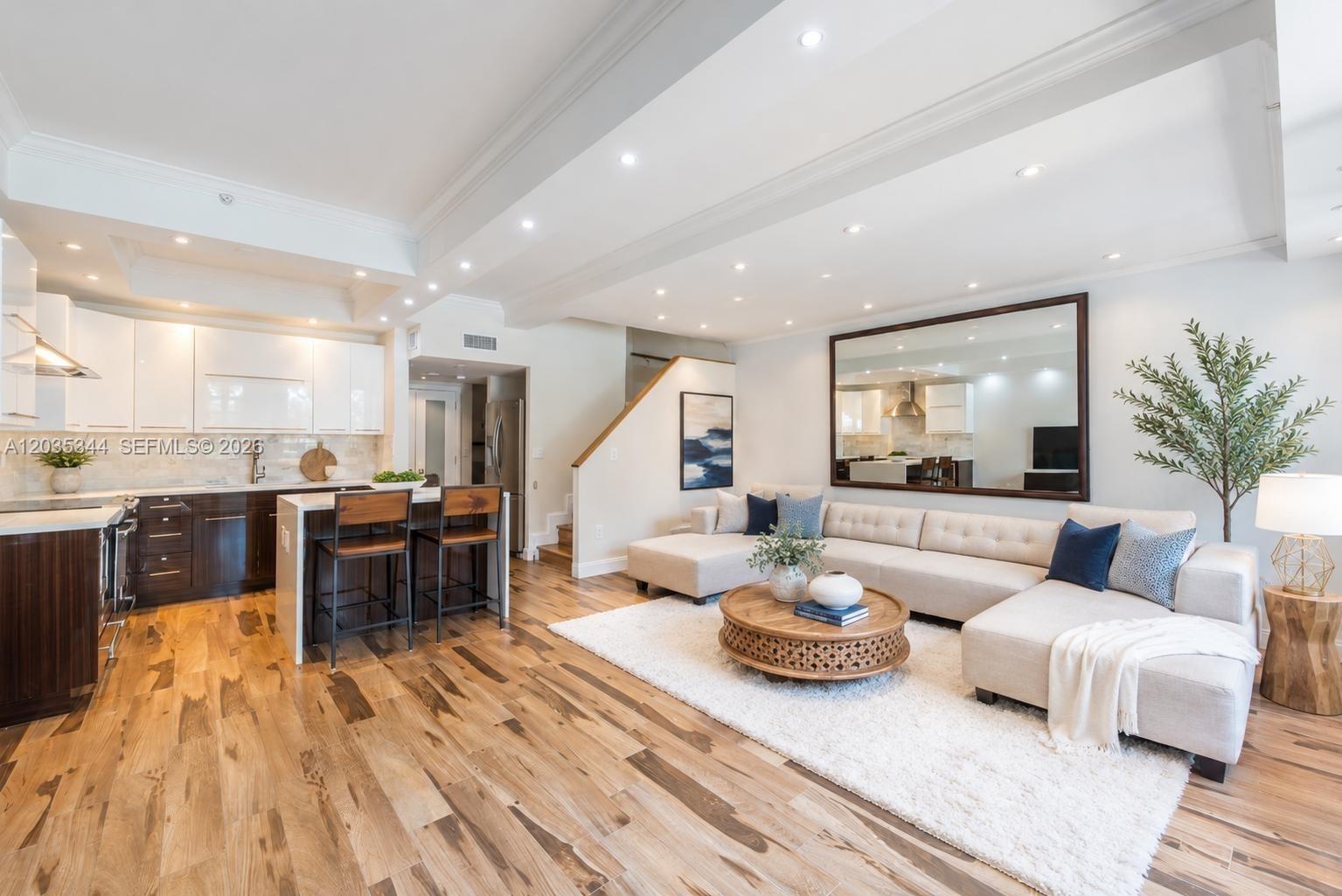 An open-concept living room and kitchen feature hardwood floors, a sectional sofa, and cabinetry — 400 S Pointe Dr # 307, Miami Beach FL 33139, MIAMI BEACH, FL