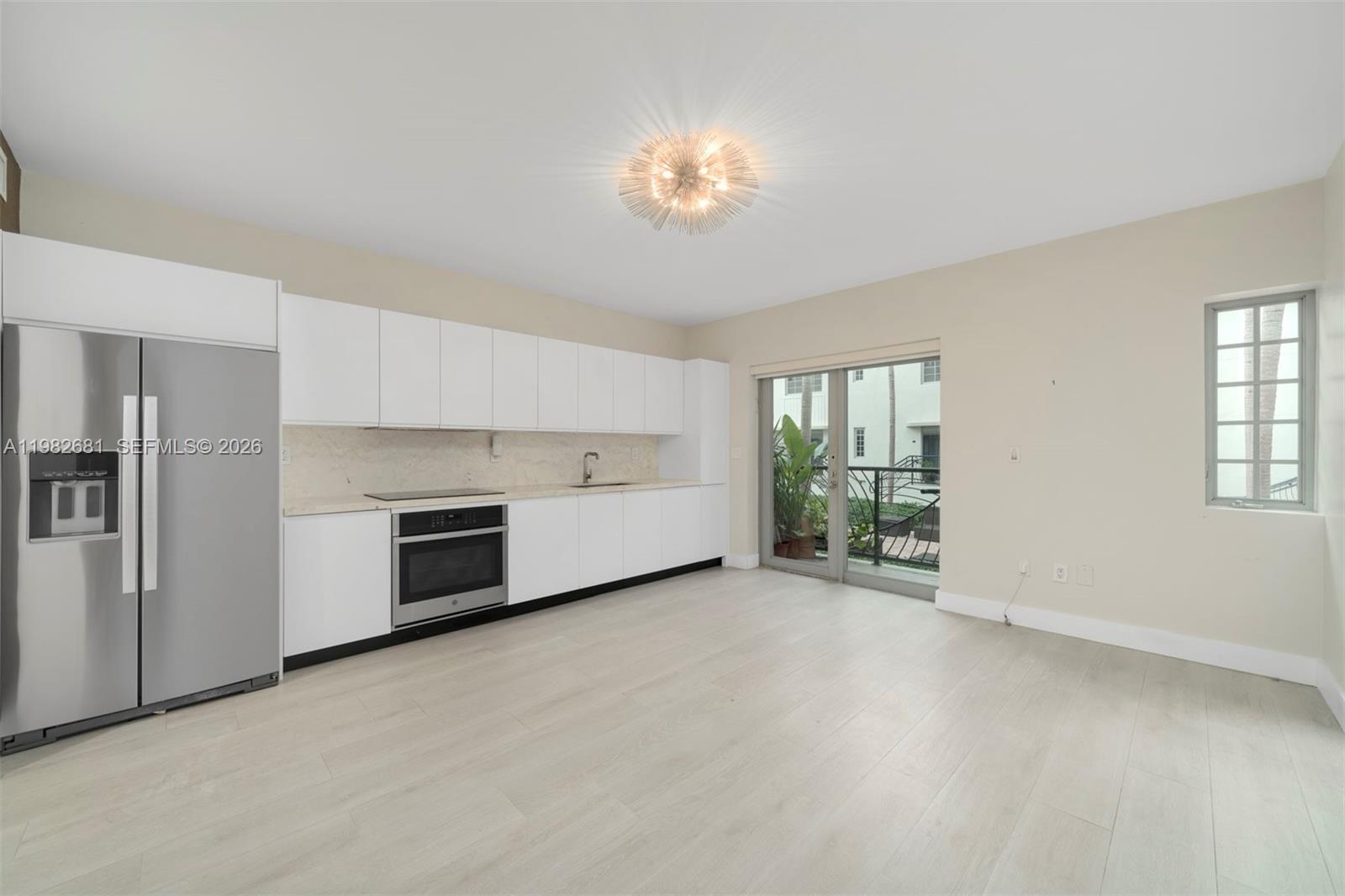 A modern kitchen features white cabinetry, stainless steel appliances, and light wood-look flooring — 435 21st St # 103, Miami Beach FL 33139, MIAMI BEACH, FL