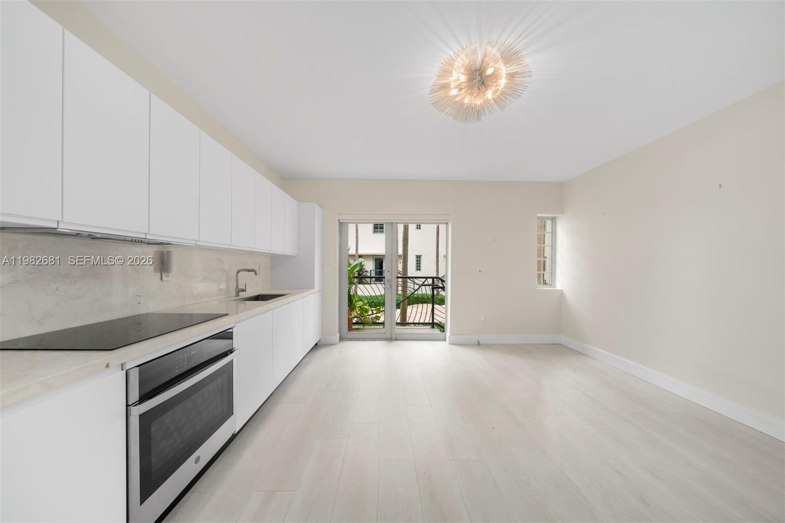 A modern kitchen features white cabinetry, stainless steel appliances, and light wood-look flooring — 435 21st St # 103, Miami Beach FL 33139, MIAMI BEACH, FL