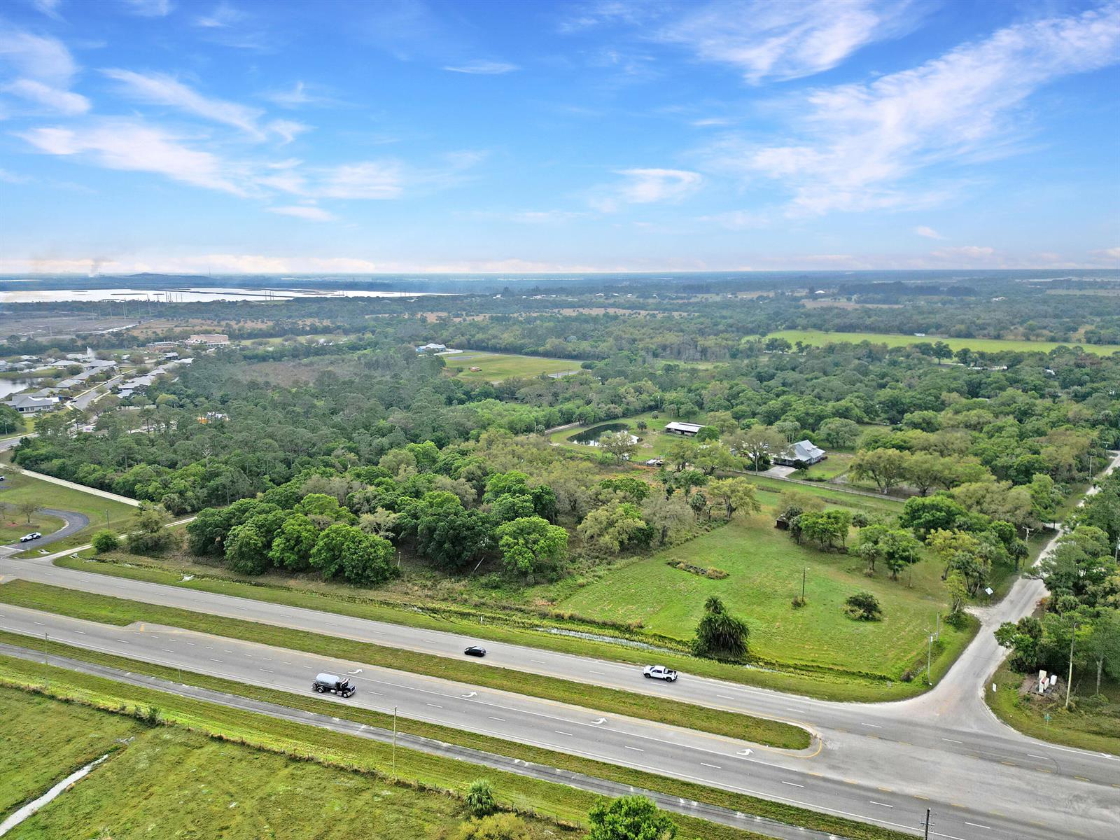 An aerial view shows a multi-lane highway bordering a large, wooded lot with a house — 11275 Okeechobee Road, Fort Pierce FL 34945, FORT PIERCE, FL