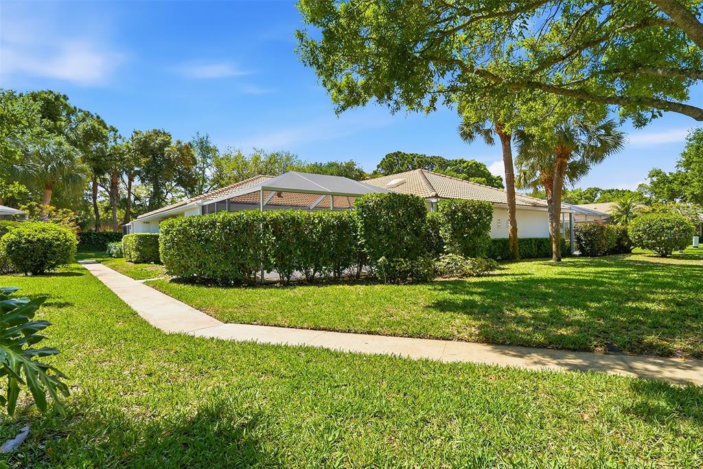 A white house with a screened-in patio is surrounded by green lawns and trimmed hedges — 9502 CHAPMAN OAK COURT, PALM BEACH GARDENS, FL