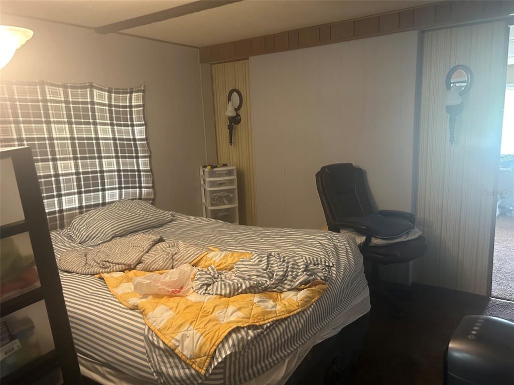 A bedroom features a bed with striped bedding, a yellow blanket, and a desk chair — 9640 SE 161ST PLACE, SUMMERFIELD, FL