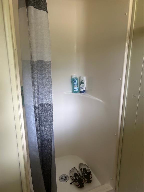 A small, white fiberglass shower stall with a gray curtain and two bottles of soap — 9640 SE 161ST PLACE, SUMMERFIELD, FL