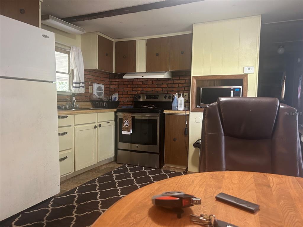 A kitchen features white cabinets, a brick backsplash, stainless steel appliances, and a dining area — 9640 SE 161ST PLACE, SUMMERFIELD, FL