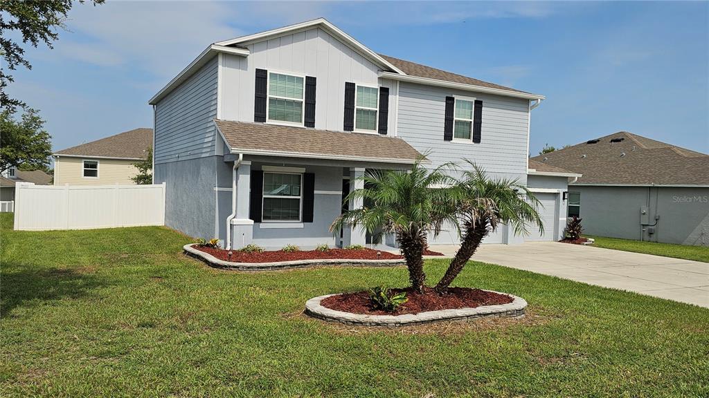 A two-story light blue house with a palm tree in the front yard — 1921 BELL CREEK LOOP, FRUITLAND PARK, FL