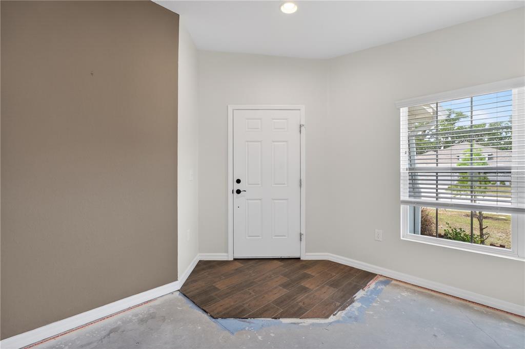 An entryway features a white door, a brown accent wall, and partial wood-look tile flooring — 1919 THOMPSON PRESERVE BOULEVARD, BARTOW, FL