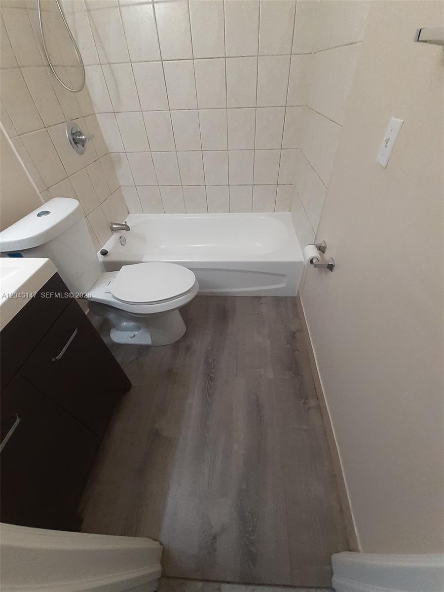 A bathroom features a white toilet, a bathtub with tiled walls, and wood-look flooring — 8480 SW 154th Cir Ct # 925, Miami FL 33193, MIAMI, FL
