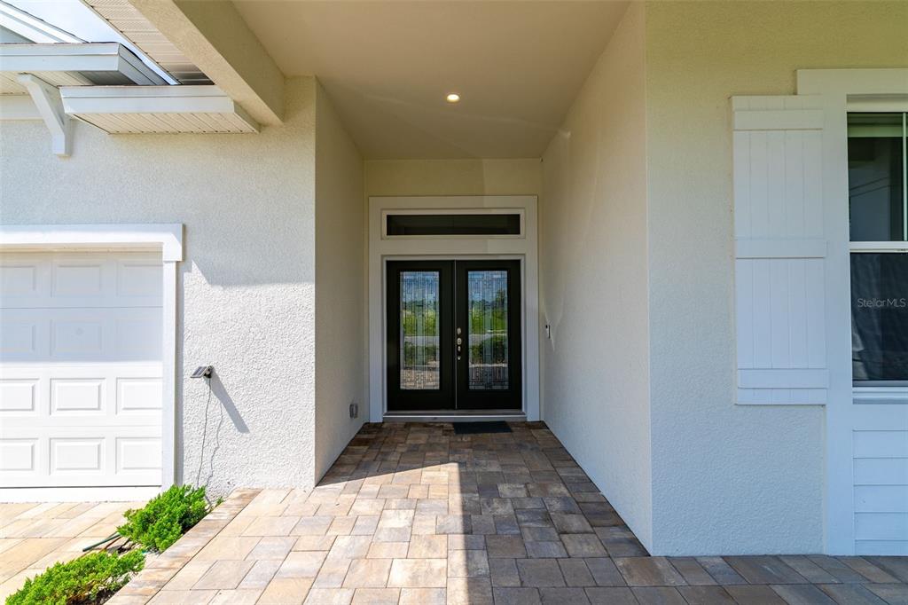 The exterior entryway features a paver walkway, double front doors, and a white garage door — 954 MEGANO BOULEVARD, DELAND, FL