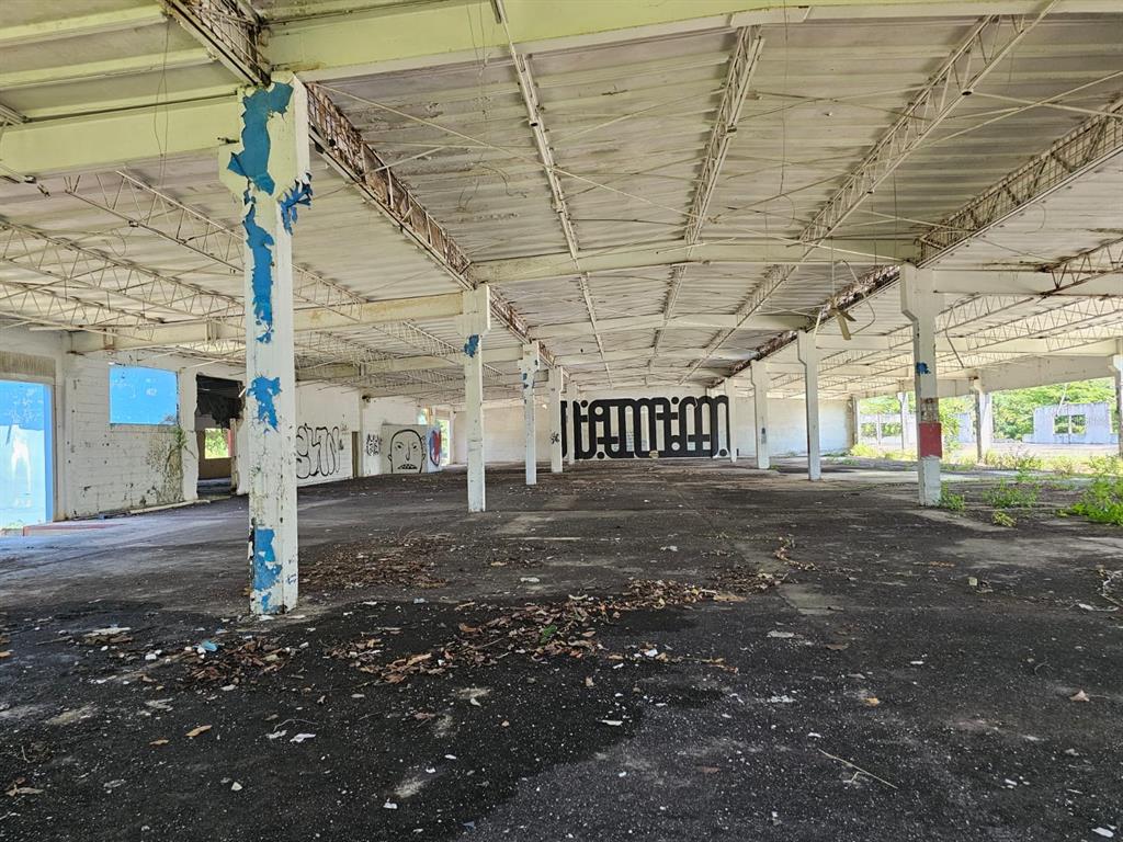 An interior view of a large, abandoned industrial warehouse with concrete floors and exposed beams — LOT 1 PR 174 KM 22.7 SONADORA WARD, AGUAS BUENAS, PR