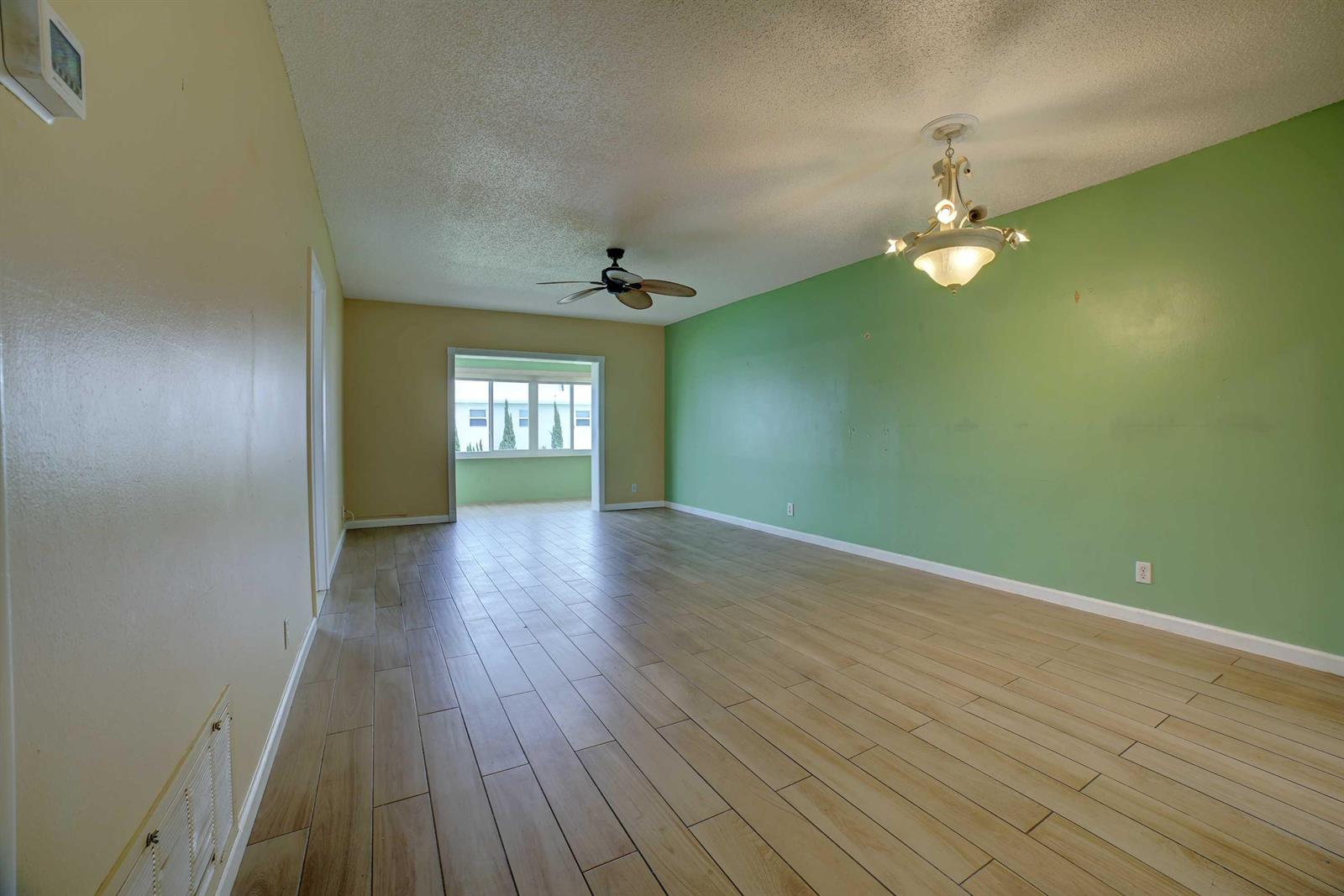 An empty room features light wood-look tile flooring, a green accent wall, and a ceiling fan — 1118 Lake Terrace # 204, Boynton Beach FL 33426, BOYNTON BEACH, FL