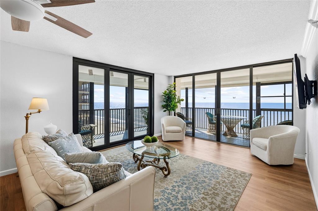 A living room features a beige sofa, two armchairs, and floor-to-ceiling windows overlooking the ocean — 15462 GULF BOULEVARD UNIT 601, MADEIRA BEACH, FL