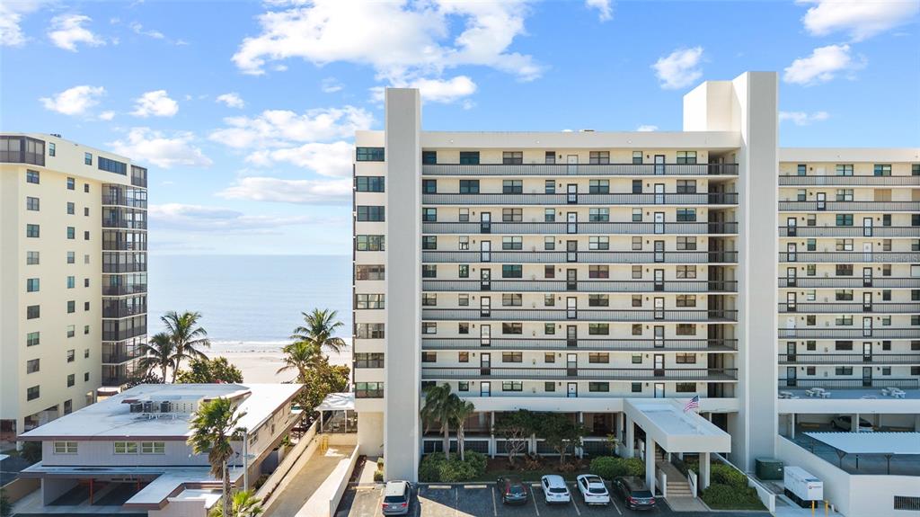 An aerial view shows a multi-story apartment building near a beach with a parking lot — 15462 GULF BOULEVARD UNIT 601, MADEIRA BEACH, FL
