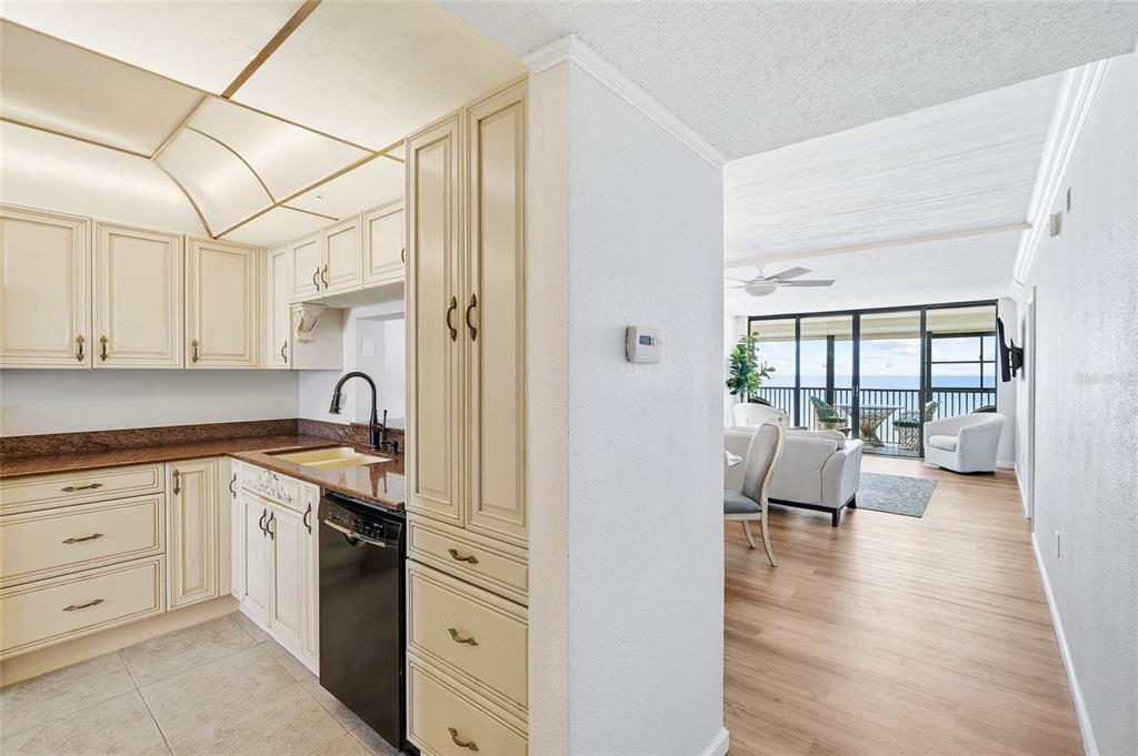A kitchen with cream cabinets and granite countertops opens into a living area with ocean views — 15462 GULF BOULEVARD UNIT 601, MADEIRA BEACH, FL