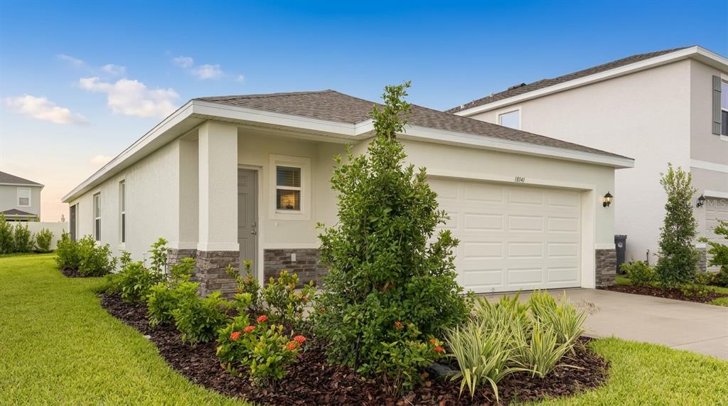 A single-story house with a white garage, stone accents, and a landscaped front yard — 18141 GANDER TERRACE, LAKEWOOD RANCH, FL