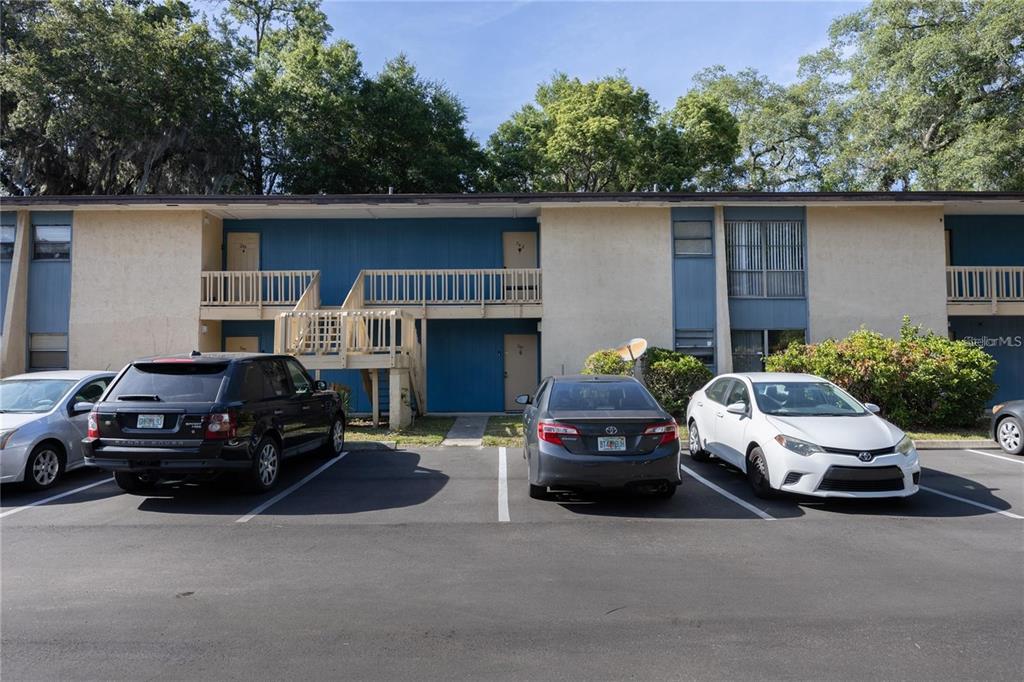 A two-story apartment building exterior features a wooden staircase and a paved parking lot — 2811 SW ARCHER ROAD UNIT Z247, GAINESVILLE, FL