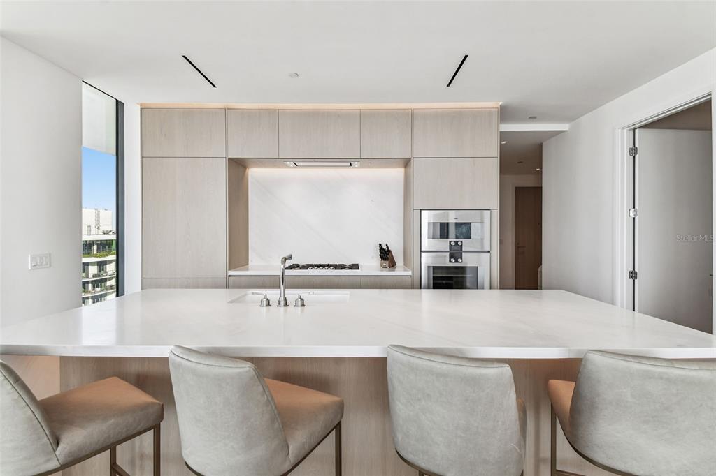 A modern kitchen features a large white marble island, light wood cabinetry, and stainless appliances — 1000 WATER STREET UNIT 2202, TAMPA, FL