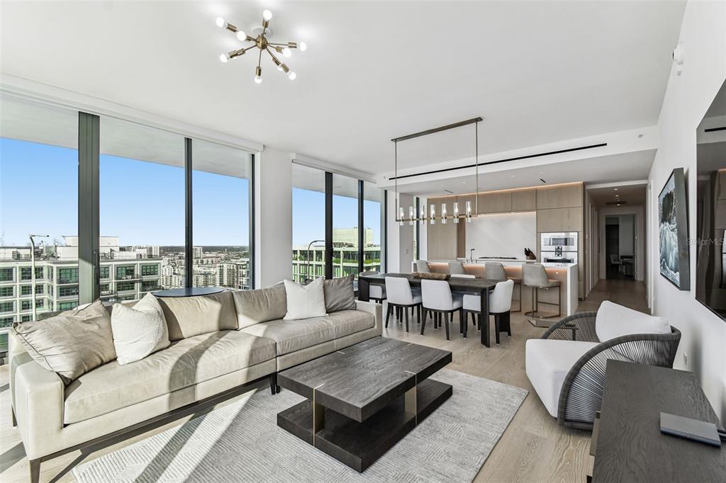 A modern open-concept living and dining area features floor-to-ceiling windows and light wood flooring — 1000 WATER STREET UNIT 2202, TAMPA, FL