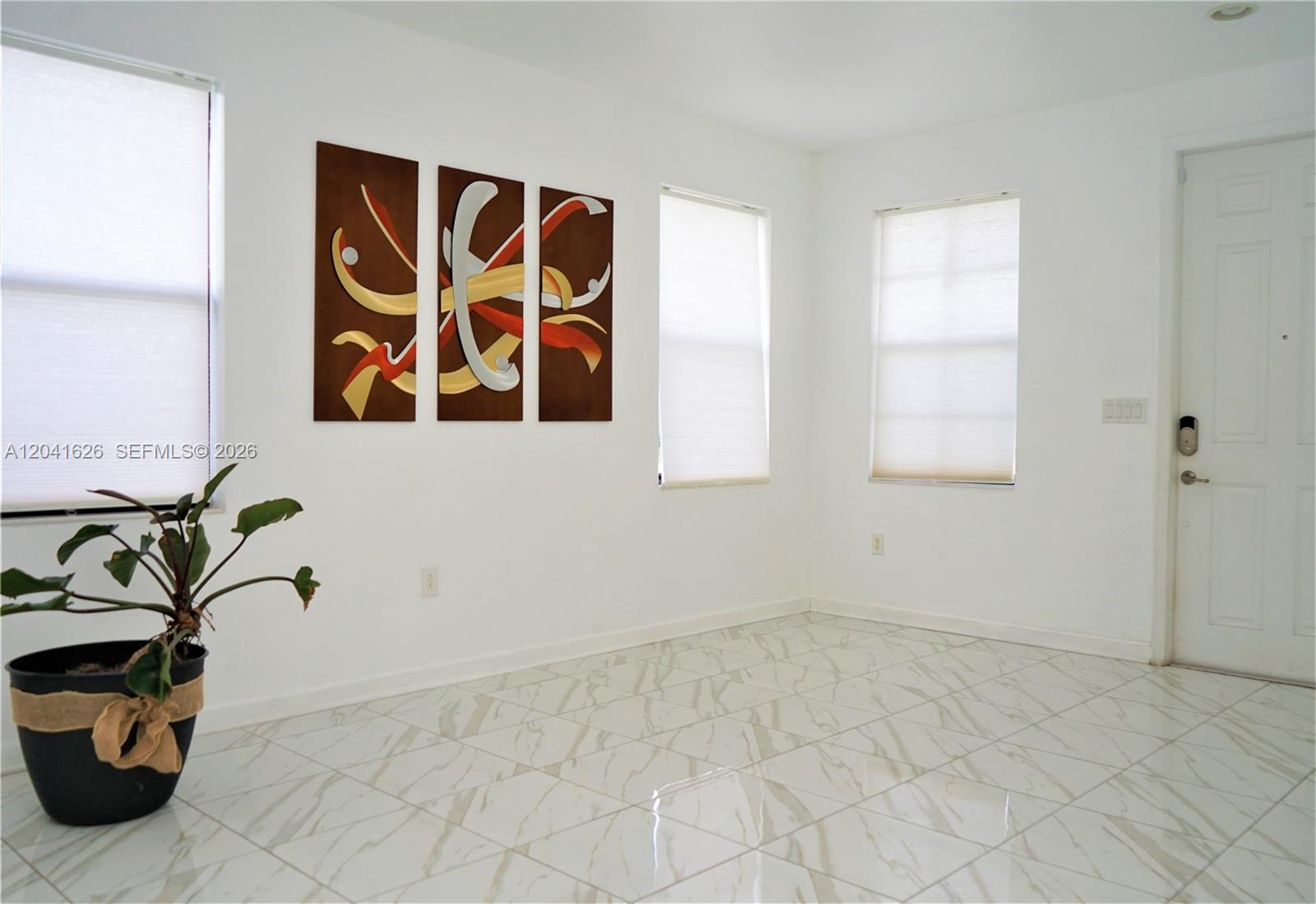 A bright room features white walls, light-colored marble-look tile flooring, three windows, and wall art — 3365 W 91st Ter # 3365, Hialeah FL 33018, HIALEAH, FL