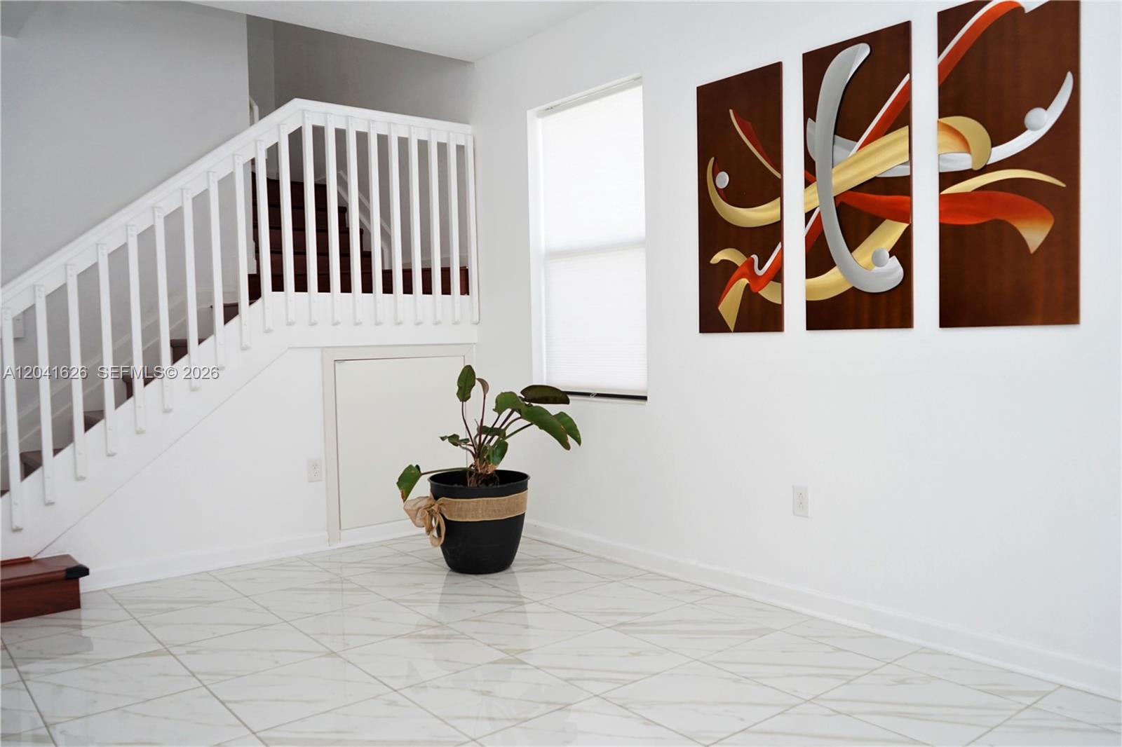 A white-walled room features a staircase, a potted plant, and three abstract wall art panels — 3365 W 91st Ter # 3365, Hialeah FL 33018, HIALEAH, FL