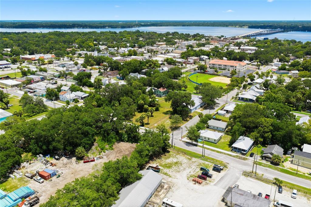 An aerial view shows a town with a large green field, residential houses, and water — 219 S 10TH STREET, PALATKA, FL