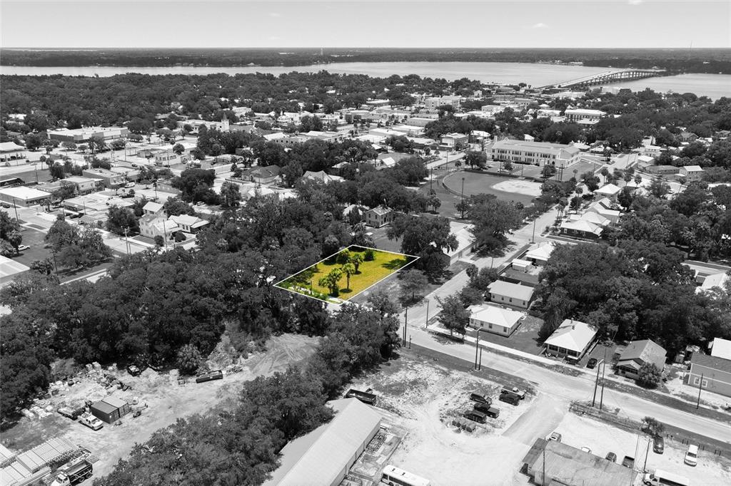 An aerial view shows a rectangular, grass-covered vacant lot highlighted in yellow amidst a neighborhood — 219 S 10TH STREET, PALATKA, FL
