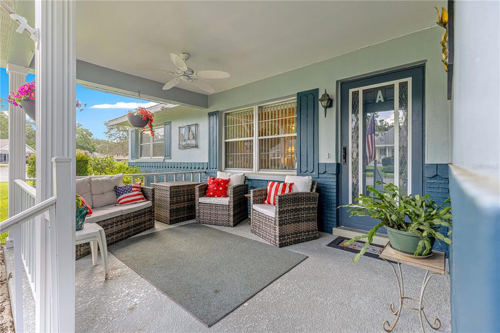 A covered front porch features wicker furniture, a ceiling fan, and a blue front door — 8662 SW 96TH LANE UNIT A, OCALA, FL