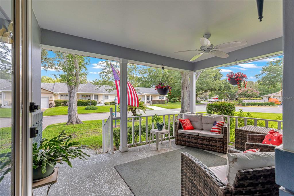A covered porch features wicker furniture, a ceiling fan, and a view of the neighborhood — 8662 SW 96TH LANE UNIT A, OCALA, FL