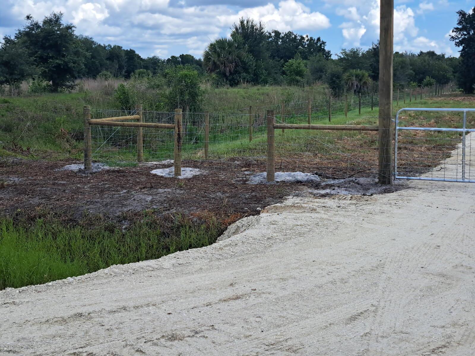 A dirt road leads to a metal gate and a newly installed wooden fence — 20639 NW 300th Street, Okeechobee FL 34972, OKEECHOBEE, FL